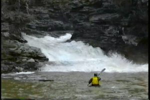 Mike Camp in a kayak looking back at Wolf Creek's convoluted waterfall